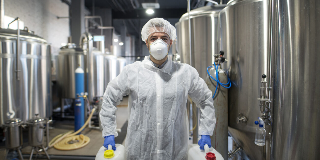 industrial worker holding plastic cans with chemicals in production plant.