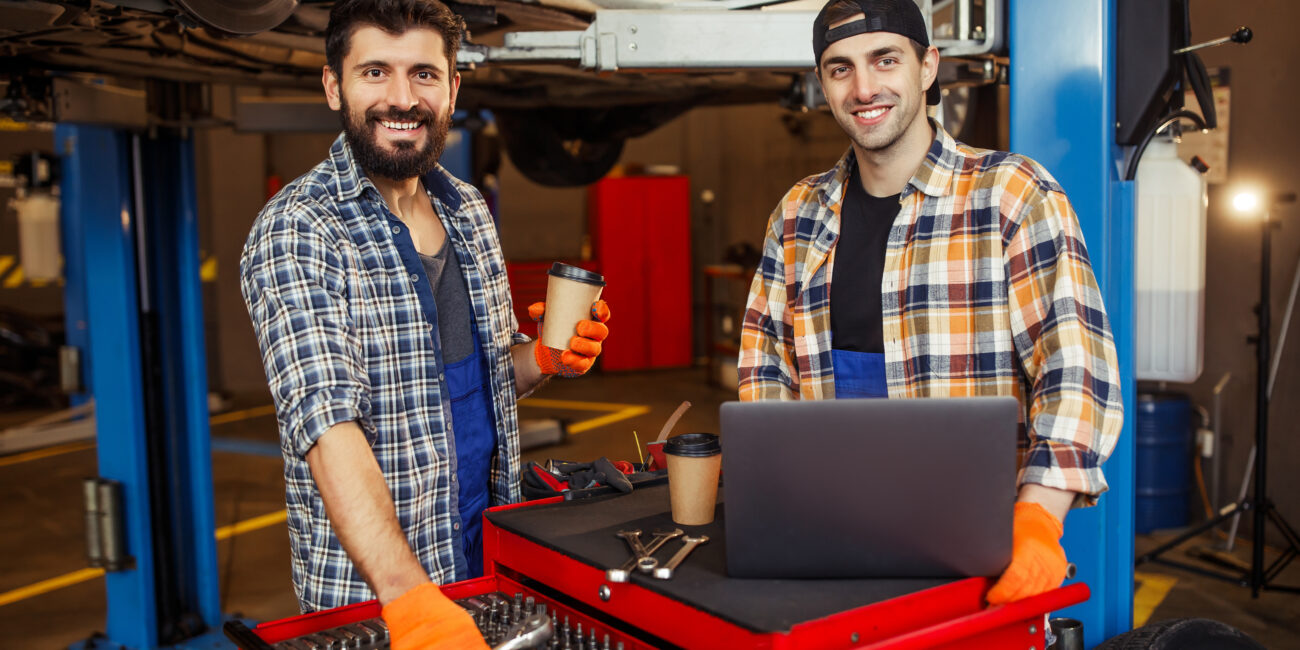 portrait of two smiling specialists working on laptop computer and looking at the camera in the modern service center